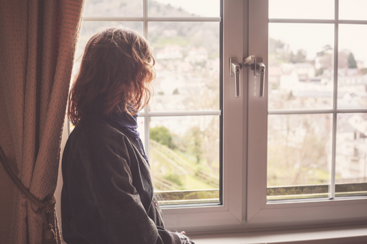 Quiet moment of reflection by a window after an intense caregiving season